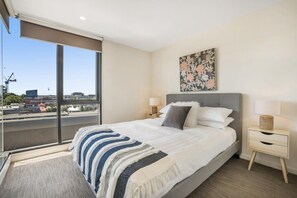 Enjoy a city view from the large bed, featuring a striped blanket, and a bedside table with a lamp and decorative item.
