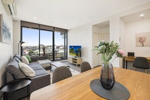 Enjoy the city view from this stylish living room with a dining table, sofa, and TV.