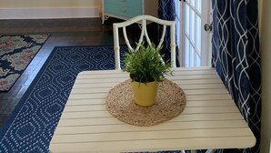 Ein Zimmer mit einem weißen Tisch, einem blau gemusterten Vorhang, einem türkisfarbenen Schrank und einem Fenster mit Jalousien.