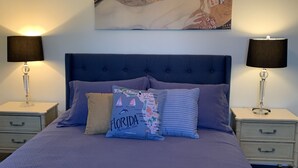 Ein Schlafzimmer mit einem großen Bett, zwei Nachttischen, einem Deckenventilator und einem Wandbild.