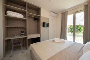 Un dormitorio con una cama, un escritorio y una silla. Hay un televisor montado en la pared y un equipo de aire acondicionado sobre la puerta.