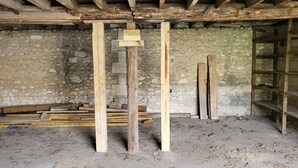 A room with exposed wooden beams, a stone wall, and scattered construction materials. - Comfortable guest rooms. (Yviers)