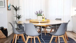 A round dining table with six grey chairs, a vase with flowers, and a bottle of wine on the table. - Private Home at the foot of Yosemite National Park (Mariposa)