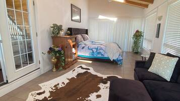 A spacious living room with a cowhide rug, a dark sofa, and a ceiling fan.