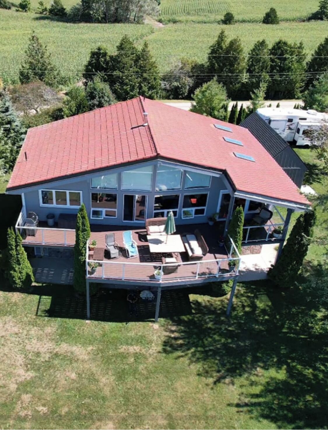 A large house with a red roof, multiple windows, and a deck with outdoor furniture.