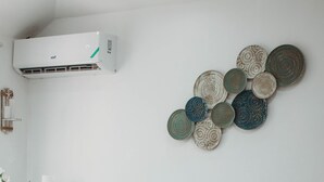 Una sala de estar con un sofá color crema, una mesa de centro de vidrio y platos decorativos en la pared.