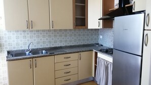 A kitchen with beige cabinets, a stainless steel Bosch refrigerator, a granite countertop, and a tiled backsplash.