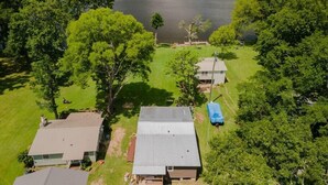 A residential area with a large lake, surrounded by dense trees and several houses with metal roofs.