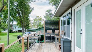 A wooden deck with outdoor furniture, a green door, and a mailbox.