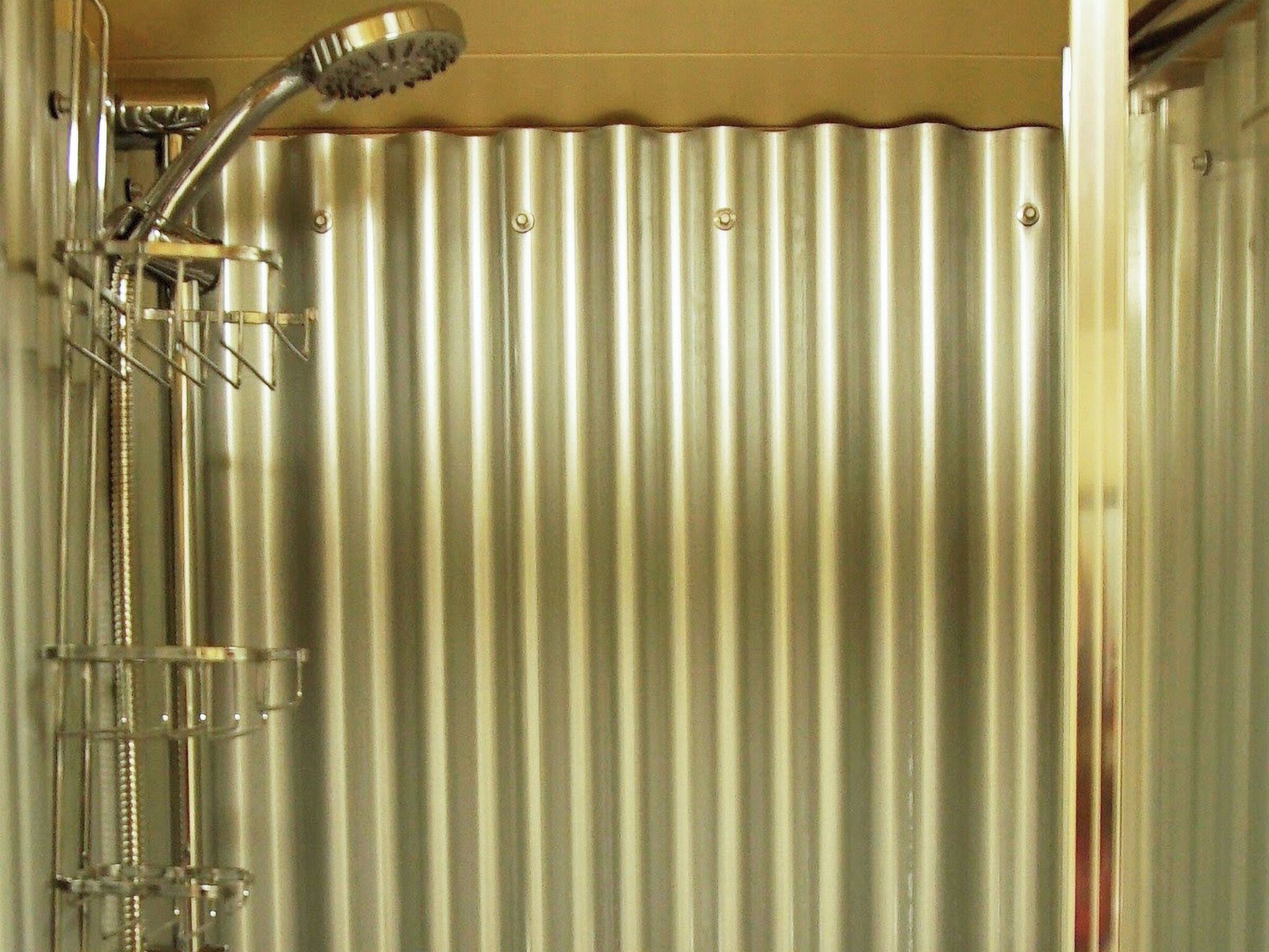A shower with a chrome head and a vertical rain showerhead.