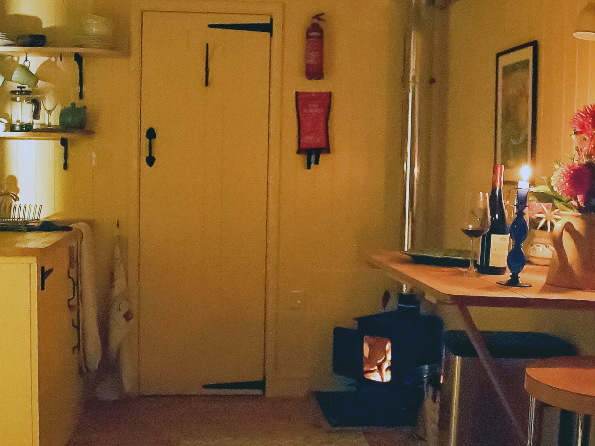 A cozy room with a wooden door, a small table with a candle, and a vase with flowers.