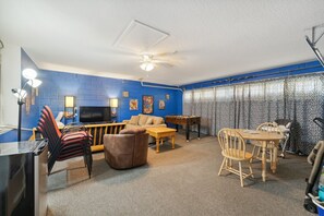 Cozy living space with a sofa, coffee table, dining table, and TV.