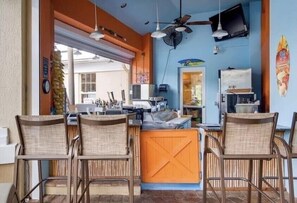 Relax in this cozy space with a central island counter, wicker chairs, and a ceiling fan.