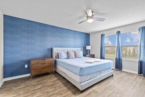 Relax in this serene bedroom with a large bed, nightstand, and ceiling fan.