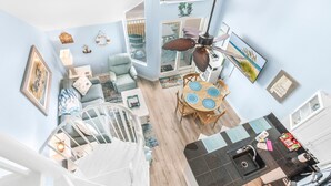A spacious living area with a dining table, a kitchen with a black countertop, and a view of the outdoors. - Top Floor with Amazing views of the Gulf - steps from the State Park Trails (Gulf Shores)