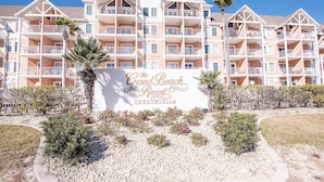 A multi-story hotel with balconies and a sign reading "The Grand Beach Resort Condominium". - Top Floor with Amazing views of the Gulf - steps from the State Park Trails (Gulf Shores)