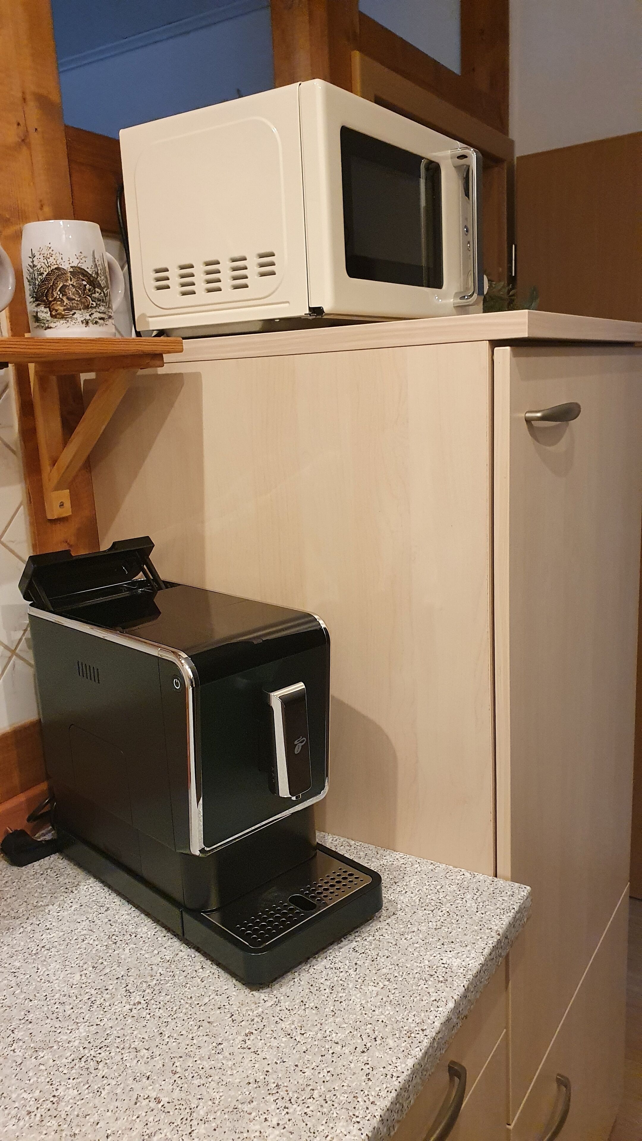 A kitchen with a microwave on top of a cabinet, a toaster on the counter, and a coffee maker.
