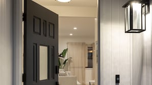 A modern entryway with a dark door, a light-colored interior, and a welcoming mat. - Pet & Kid-Friendly Beach Retreat Near Town  +EVC , Fire Pit , Beach & Baby Gear! (Santa Barbara)