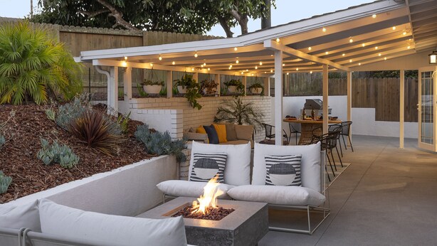 An outdoor patio with a fire pit, seating area, and a covered dining space with string lights. - Pet & Kid-Friendly Beach Retreat Near Town  +EVC , Fire Pit , Beach & Baby Gear! (Santa Barbara)