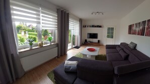 Ein modernes Wohnzimmer mit einem dunkelgrauen Sofa, einem weißen Couchtisch und einem flachbildfernseher, der an der Wand befestigt ist.