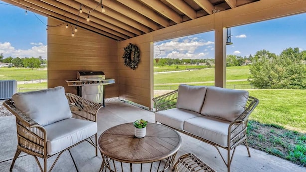 A covered patio with wicker furniture, a grill, and a view of a grassy field. - Inviting 5 Bedroom Home Centrally Located (Colorado Springs)