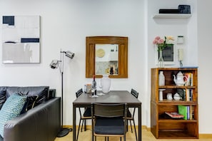 A modern living space with a dining table, chairs, a black leather sofa, a bookshelf, and a mirror. - Lovely home in the center of Rome, Fabrizia. (Roma)