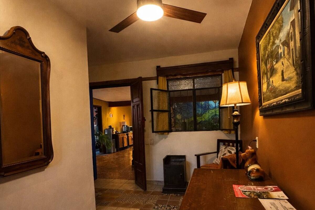 A room with a ceiling fan, a dining table with chairs, a framed picture on the wall, and a patterned floor.