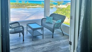 Un espacio de descanso al aire libre con mobiliario de mimbre y vista a la playa.