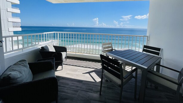 Ein Balkon mit Blick auf das Meer, ausgestattet mit einem Tisch und Stühlen sowie einem weißen Geländer.