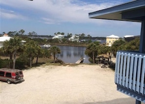 A view of a lake with a boat dock, palm trees, and a red vehicle parked on the sand.