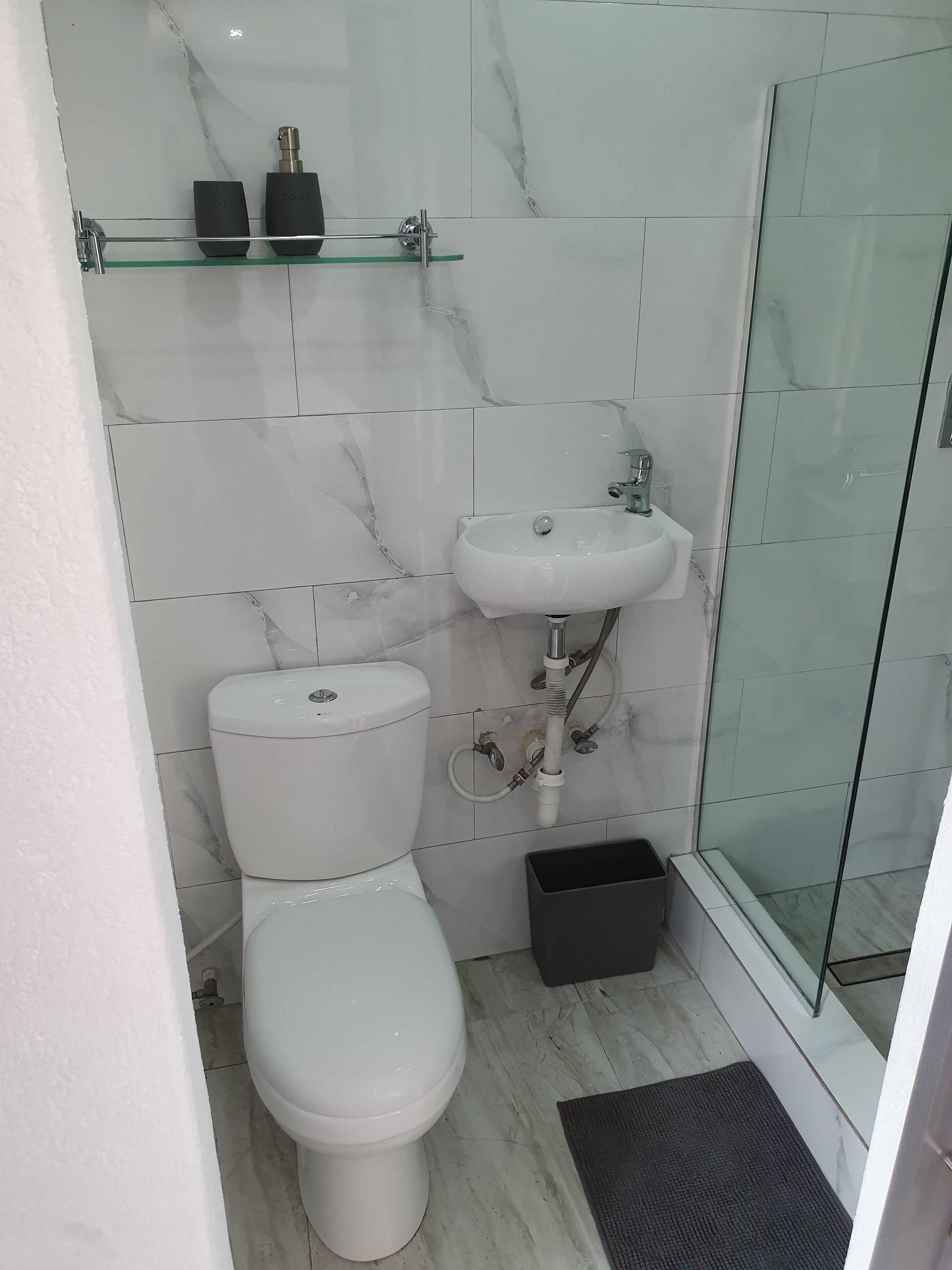 Un baño moderno con inodoro, cabina de ducha de vidrio y lavamanos.