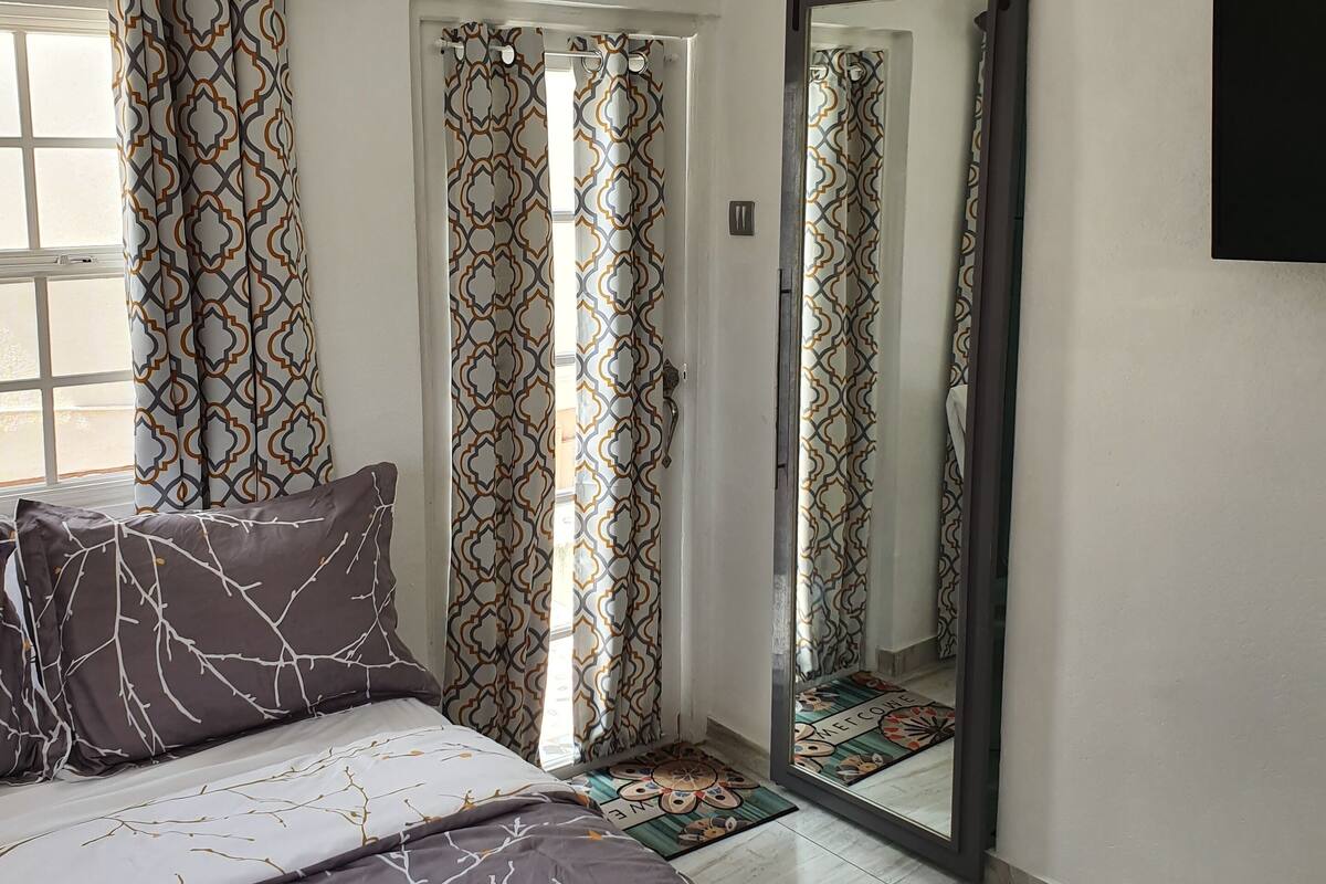 Une chambre à coucher avec un lit, des rideaux à motifs, une porte coulissante et un miroir.
