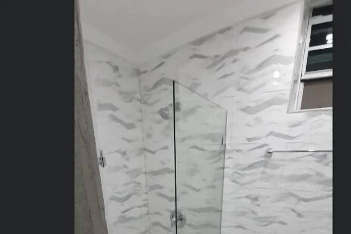Une salle de bain dotée d’une douche à parois de verre, de toilettes et d’un mur décoré d’un motif imitant le marbre.