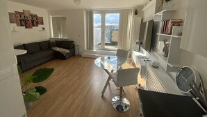 Una sala moderna con una mesa de comedor de vidrio, un sofá y un ventanal con vistas a la ciudad.