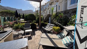Un patio al aire libre con sillones, una mesa y plantas en macetas.