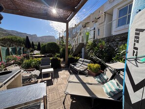 Eine Terrassensitzgelegenheit mit Lounge-Möbeln, einem Tisch und Blumentöpfen.