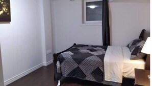 Una camera da letto con un letto, una finestra con tende, una lampada a soffitto e un quadro appeso al muro.