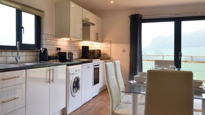 A modern kitchen with a washing machine, a coffee maker, and a dining area with a view. - Offa's Dyke Lodge - UK10835 (Stanner, near Kington)