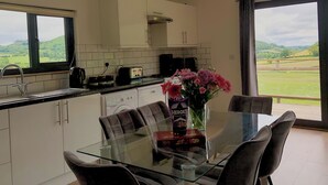A modern kitchen with a dining area, large windows, and a view of the countryside. - Offa's Dyke Lodge - UK10835 (Stanner, near Kington)