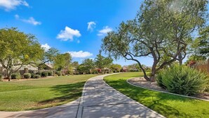 A residential street with a curved sidewalk, houses, and trees.