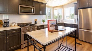 A modern kitchen with dark cabinets, stainless steel appliances, and a marble countertop. - Casa Caballo: Vineyard views and close to downtown (Paso Robles)