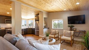 A modern living room with a grey sofa, a coffee table, and a TV mounted on the wall. - Casa Caballo: Vineyard views and close to downtown (Paso Robles)