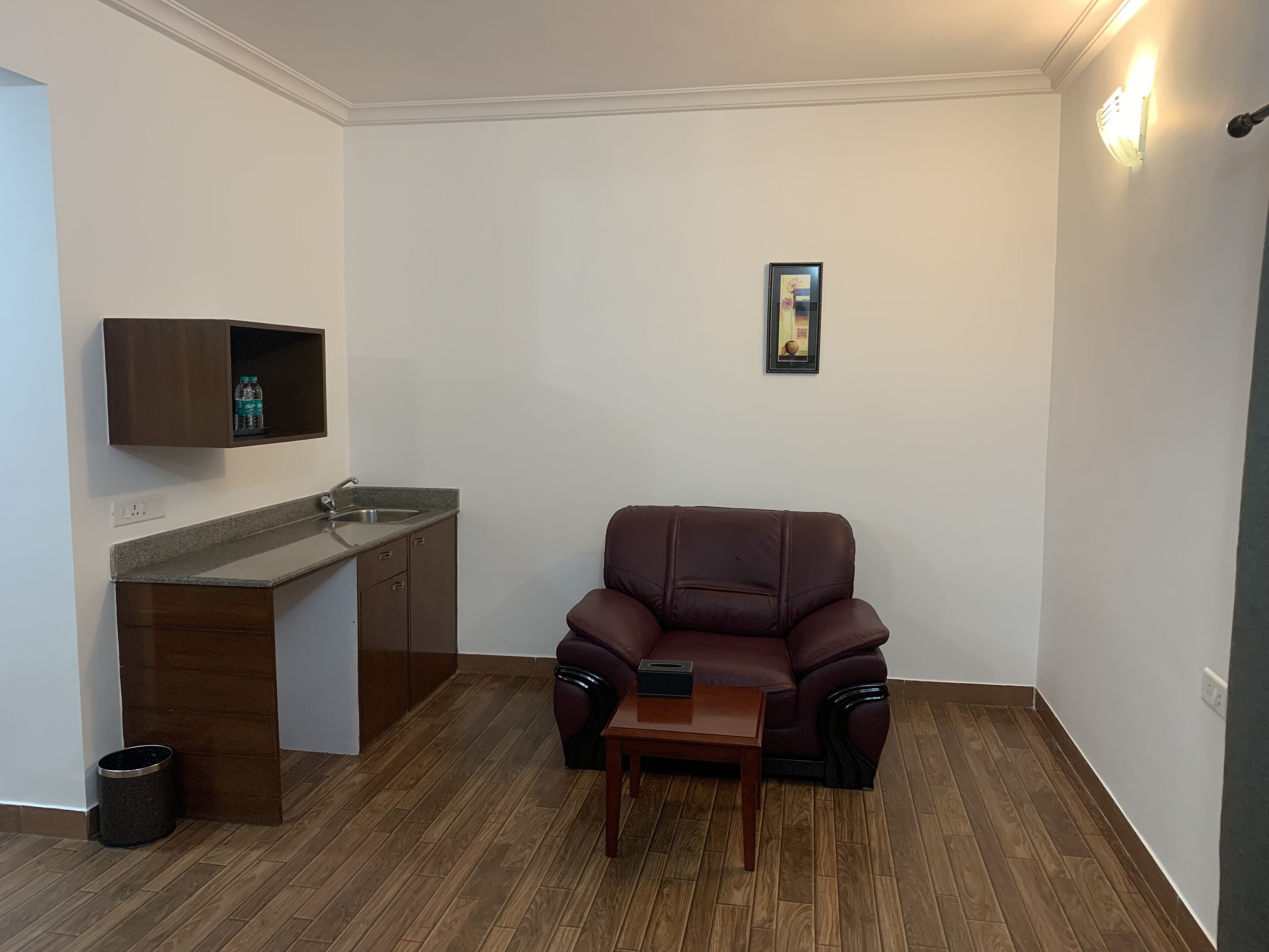 A compact living space with a kitchenette, a brown leather sofa, and a small wooden table.