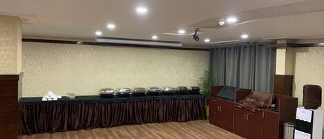 A conference room with a long table, a sofa, and a small kitchenette.