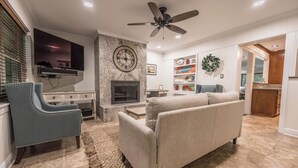Ein Wohnzimmer mit Kamin, Deckenventilator und Wandfernseher.