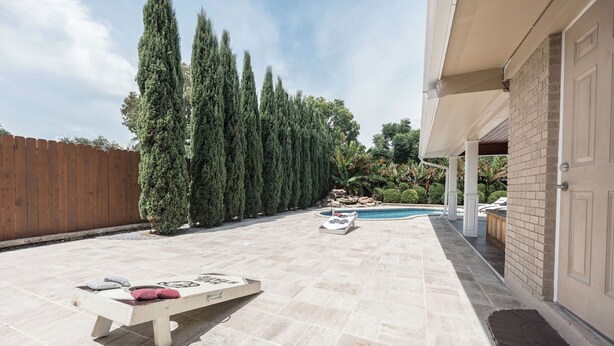 Ein Garten mit Swimmingpool, einer Holzterrasse und einer Ziegelwand.