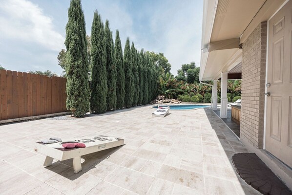 Un giardino sul retro con una piscina, un pontile in legno e un muro in mattoni.