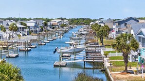 A marina with boats docked along a narrow waterway, surrounded by residential buildings and palm trees. - In the Heart of Ocean Isle privatePool! Walk to Pier, Restaurants & Shops 10beds (Ocean Isle Beach)