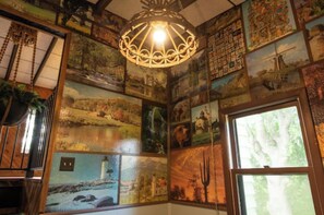 Experience a unique, artistic space with a collage of photographs and paintings adorning the walls, complemented by an ornate chandelier.
