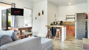 En moderne stue med en grå sofa, et træsofabord og et fjernsyn monteret på væggen.